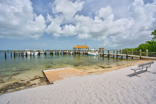 view of dock featuring a beach view and a water view