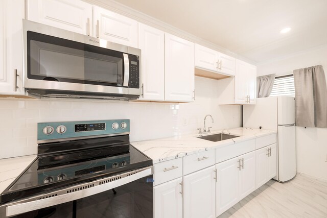 kitchen with sink, light stone countertops, white cabinets, and appliances with stainless steel finishes