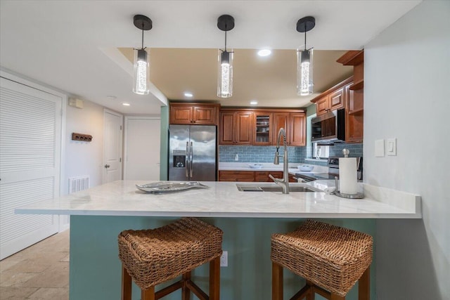 1998 Overseas Hwy Unit A31, Marathon, FL 33050 - kitchen with tasteful backsplash, a kitchen bar, a peninsula, brown cabinets, and stainless steel appliances