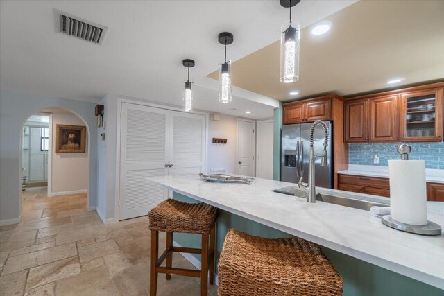 1998 Overseas Hwy Unit A31, Marathon, FL 33050 - kitchen with visible vents, brown cabinets, hanging light fixtures, stainless steel fridge with ice dispenser, and stone tile floors