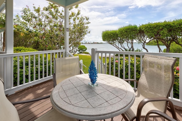 wooden deck with a water view and outdoor dining space