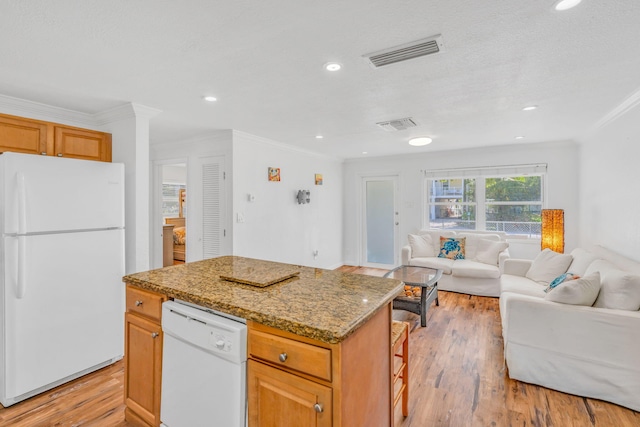 kitchen with light stone counters, white appliances, a center island, and light wood-type flooring