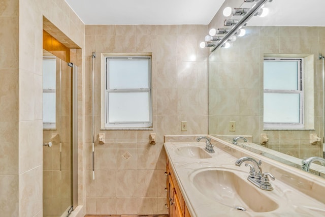 bathroom with vanity, tile walls, and a shower with shower door