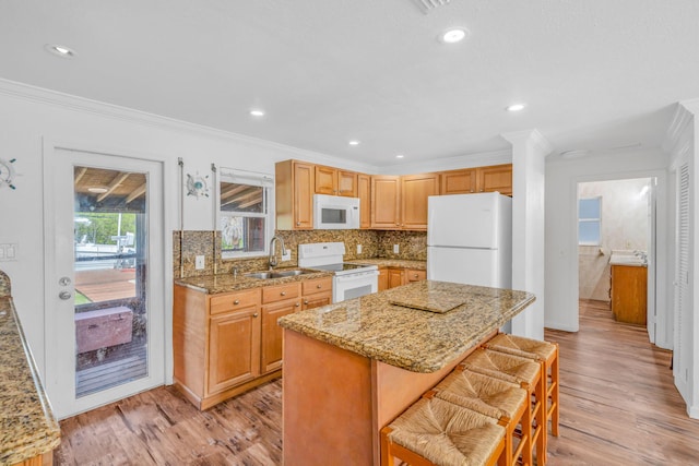 kitchen featuring sink, white appliances, a center island, a kitchen bar, and decorative backsplash