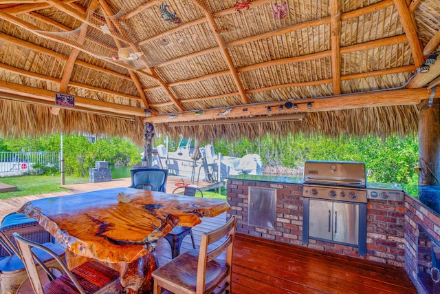 view of patio with area for grilling, a gazebo, a wooden deck, a bar, and exterior kitchen