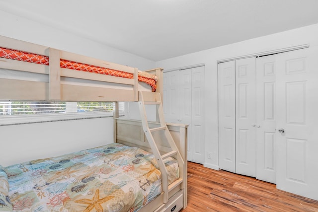 bedroom with two closets and light wood-type flooring