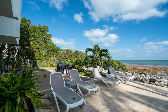 view of patio / terrace with a view of the beach, area for grilling, and a water view