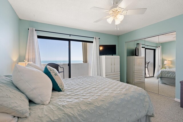 carpeted bedroom with ceiling fan, a closet, and a textured ceiling