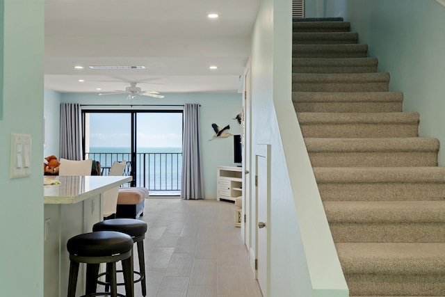 stairs with a water view and ceiling fan