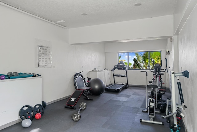 exercise room with a wall unit AC and a textured ceiling