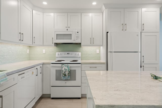 kitchen featuring white cabinetry, light stone counters, light hardwood / wood-style flooring, white appliances, and backsplash