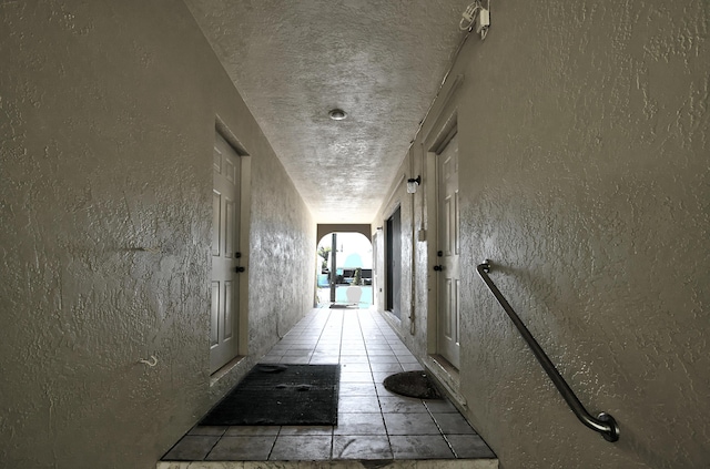 hall with light tile patterned flooring and a textured ceiling