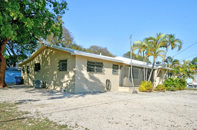 view of front of home featuring central AC, a sunroom, and stucco siding