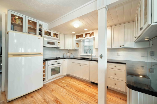 kitchen with white cabinetry, sink, white appliances, and light hardwood / wood-style flooring