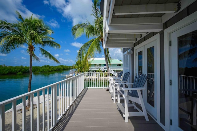 wooden terrace with a water view and french doors