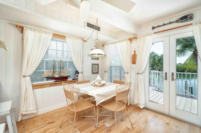 dining space with beam ceiling, french doors, and light wood-type flooring