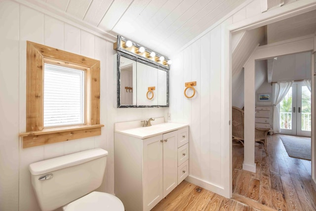 bathroom featuring vaulted ceiling, hardwood / wood-style flooring, vanity, toilet, and french doors