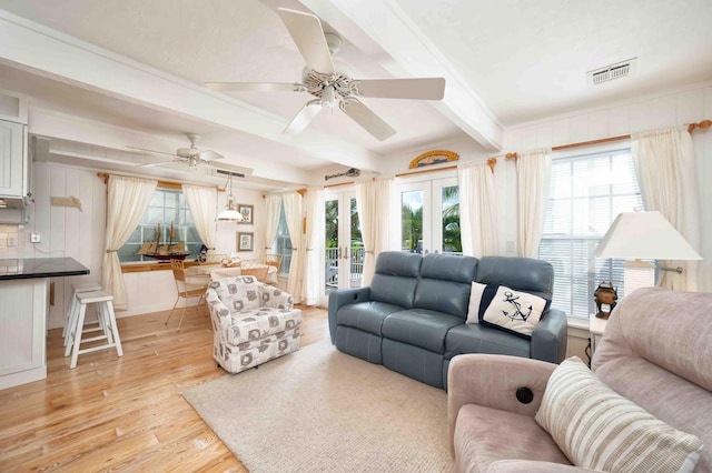 living room featuring beam ceiling, light hardwood / wood-style flooring, french doors, and ceiling fan