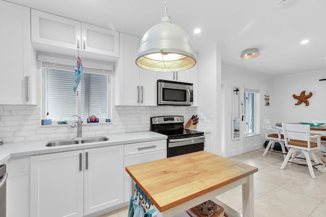 kitchen with appliances with stainless steel finishes, tasteful backsplash, sink, white cabinets, and hanging light fixtures