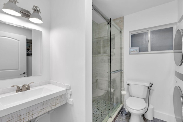 bathroom with a shower with door, stacked washing maching and dryer, sink, and toilet