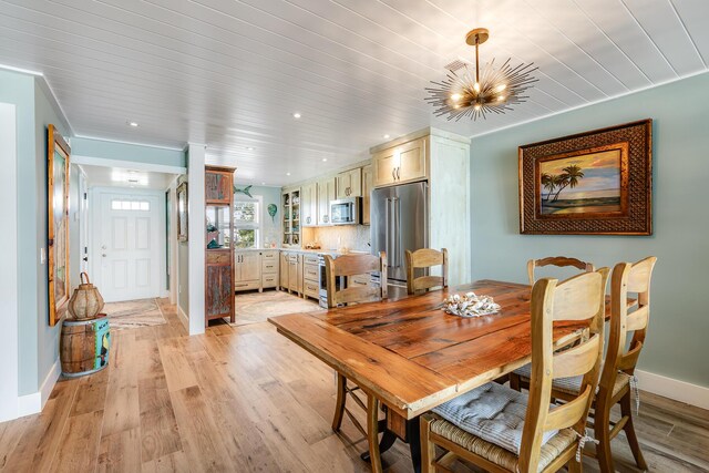 dining area with light hardwood / wood-style floors, wooden ceiling, and a chandelier