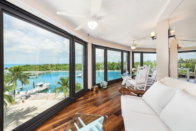 sunroom featuring ceiling fan and a water view