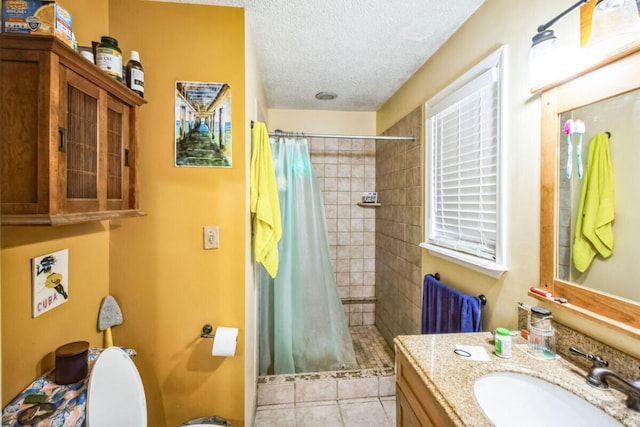 bathroom with tile patterned floors, toilet, a stall shower, a textured ceiling, and vanity