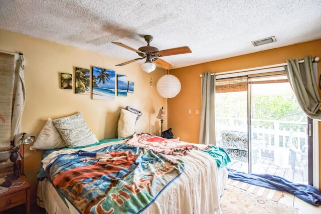 bedroom with access to exterior, visible vents, a textured ceiling, and a ceiling fan