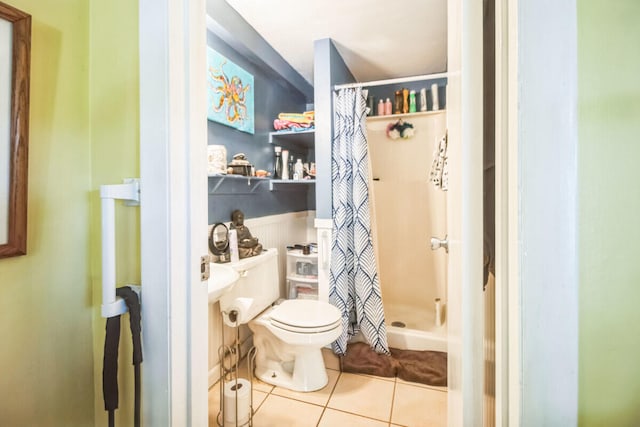 bathroom featuring toilet, wainscoting, a shower stall, and tile patterned flooring