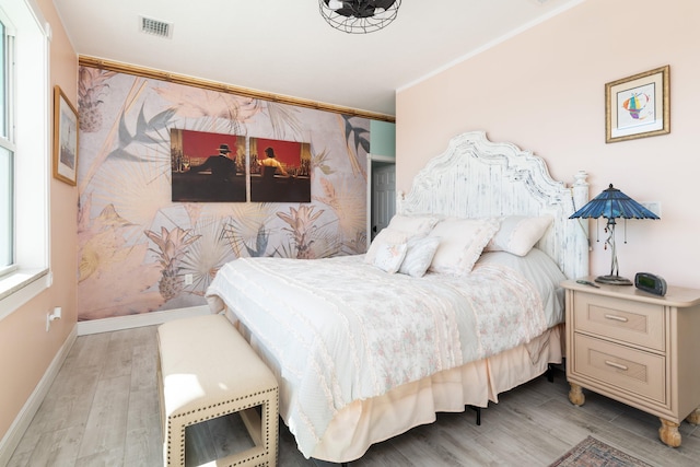 bedroom featuring crown molding and light hardwood / wood-style flooring