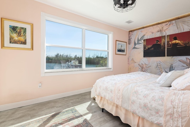 bedroom featuring hardwood / wood-style flooring and a water view