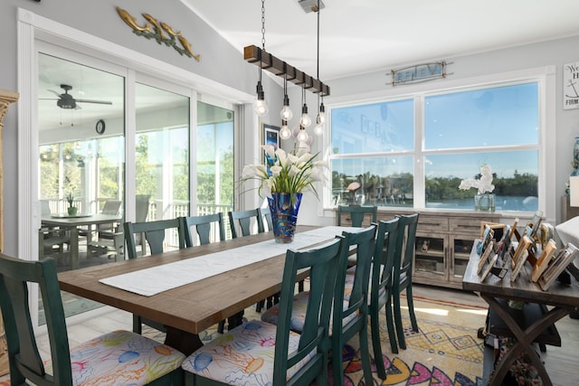 dining space featuring a water view, ceiling fan, and light wood-type flooring