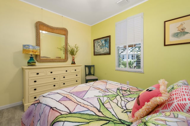 bedroom with crown molding and light hardwood / wood-style floors