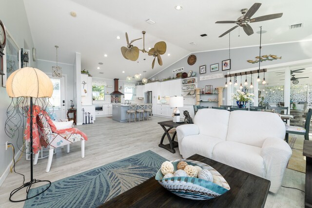 living room featuring ceiling fan, lofted ceiling, sink, and light hardwood / wood-style flooring