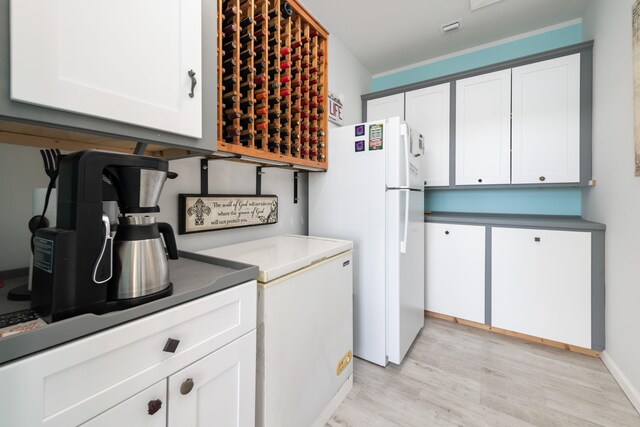 kitchen with white refrigerator, light hardwood / wood-style flooring, and white cabinets