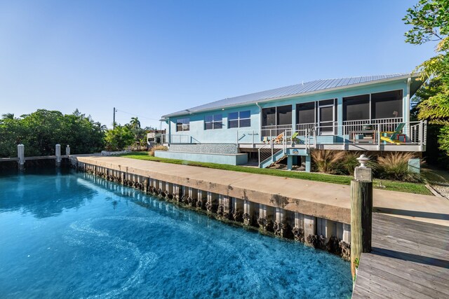 rear view of house with a water view and a sunroom