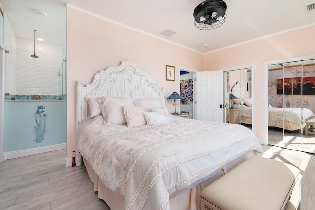 bedroom featuring ornamental molding, light wood-type flooring, and two closets