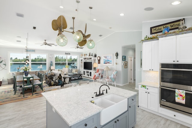 kitchen featuring pendant lighting, sink, white cabinetry, and an island with sink