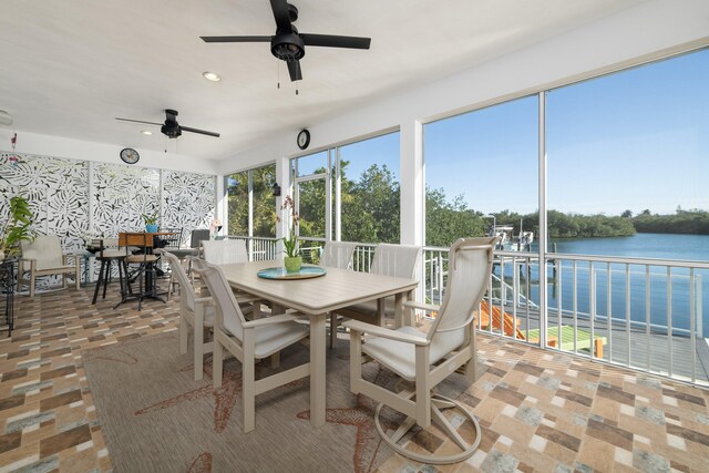 sunroom / solarium featuring plenty of natural light, ceiling fan, and a water view