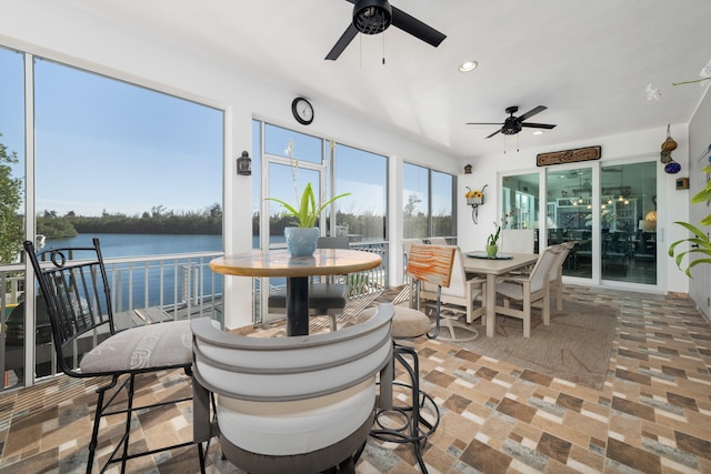 sunroom / solarium with a water view and ceiling fan