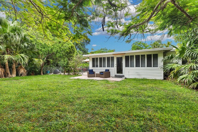 rear view of house featuring a patio, an outdoor living space, and a lawn