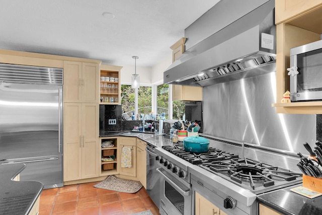 kitchen featuring pendant lighting, dark stone counters, high end appliances, light tile patterned floors, and wall chimney range hood