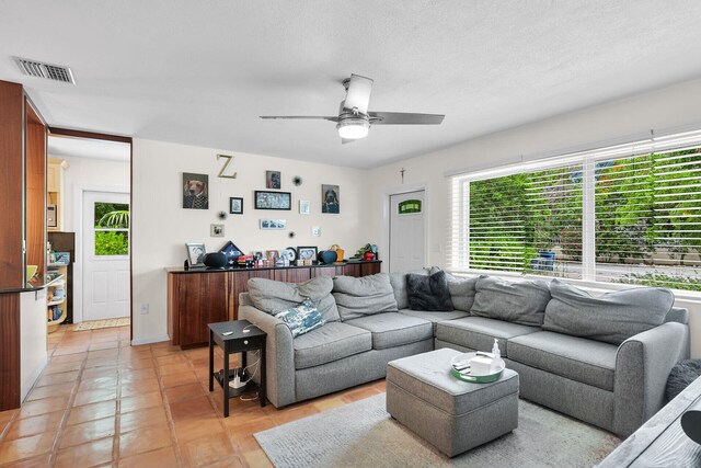 living room featuring a textured ceiling, ceiling fan, and light tile patterned flooring