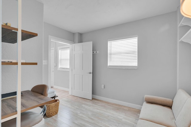 living area with wood finished floors, baseboards, and an office area