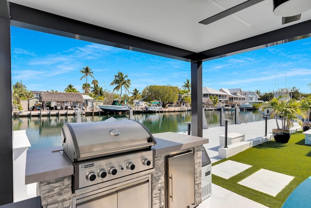 view of patio featuring grilling area, a water view, exterior kitchen, a boat dock, and a residential view