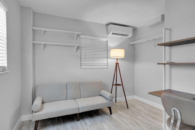sitting room with a wall unit AC, baseboards, and wood finished floors