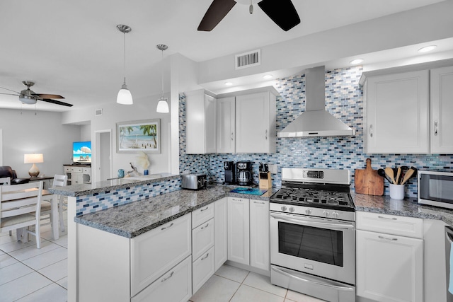 kitchen with appliances with stainless steel finishes, a ceiling fan, wall chimney exhaust hood, and a peninsula