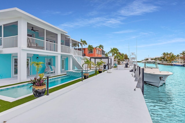 dock featuring stairway, a patio, and a pool with connected hot tub