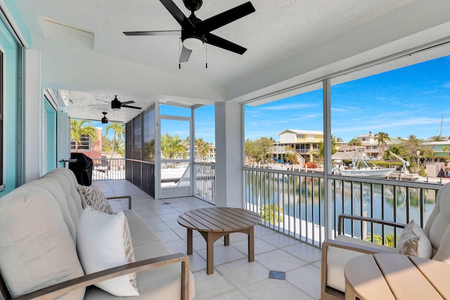 sunroom featuring ceiling fan, a water view, and an outdoor living space