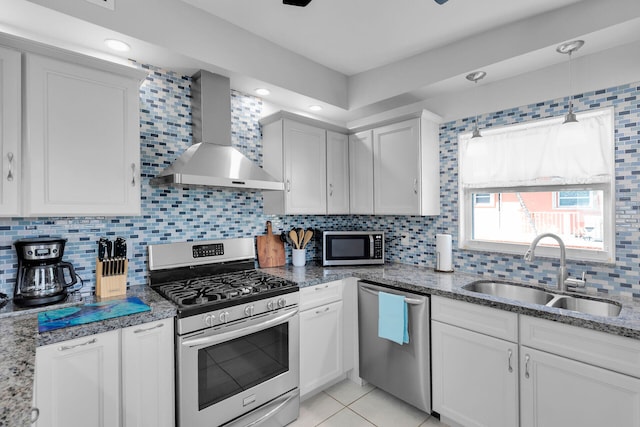 kitchen featuring appliances with stainless steel finishes, wall chimney exhaust hood, a sink, tasteful backsplash, and recessed lighting